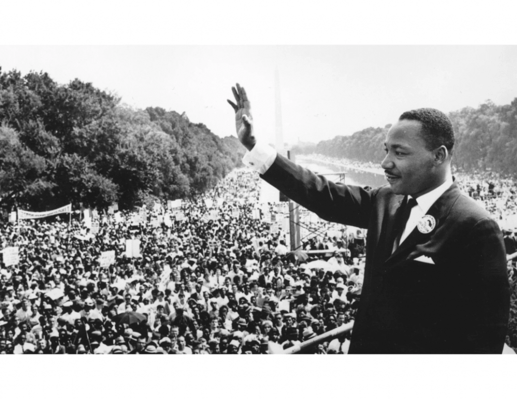 Martin Luther King Jr. waving to large crowd at Lincoln Memorial Reflecting Pool in Washington DC.