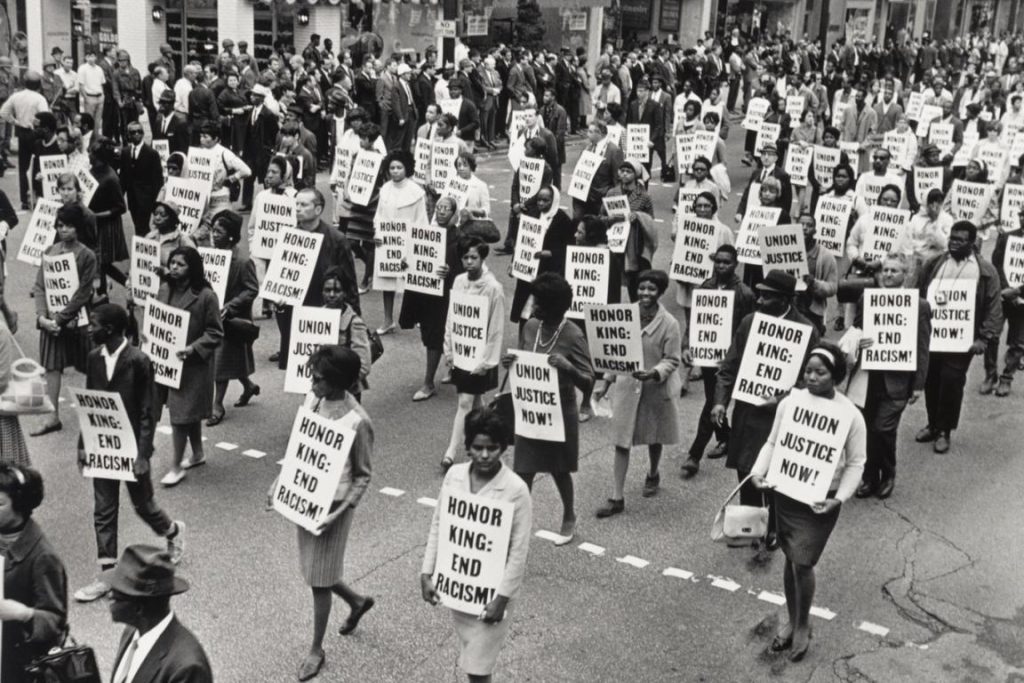 Group of protestors walking down street with signs "Honor King - End Racism!" and "Union Justice Now".
